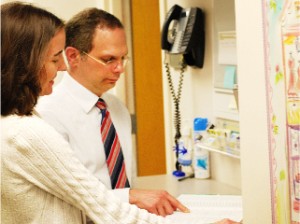 Surgeon pointing at patient file near phone in office