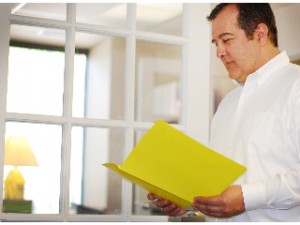 Surgeon standing, looking down at patient file